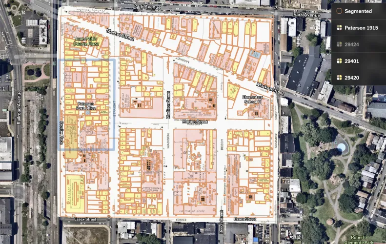 A 1915 Sanborn fire insurance map of downtown Paterson overlaid on aerial imagery, with building outlines traced in yellow